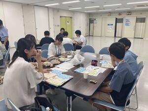職員から仕事内容を聞いている様子