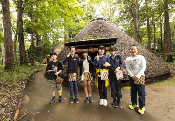 竪穴住居前で並んだ児童の写真