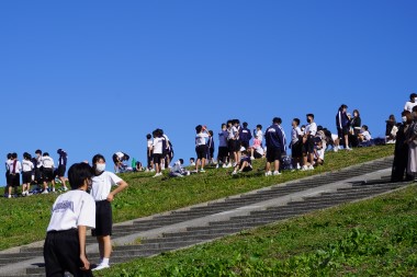 土手からゴールする生徒を見守る生徒たちの写真