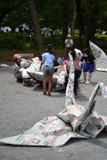 大きな鶴と大きな紙で折り紙をしている子ども達の写真