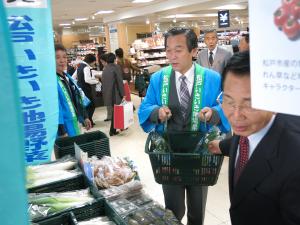 松戸特産フェアで野菜をかごに入れてる市長の写真